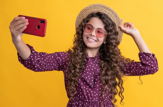 Niña sonriente con el pelo rizado tomando selfie por teléfono