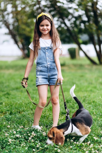 Niña sonriente de pie con un perro y mirando a la cámara