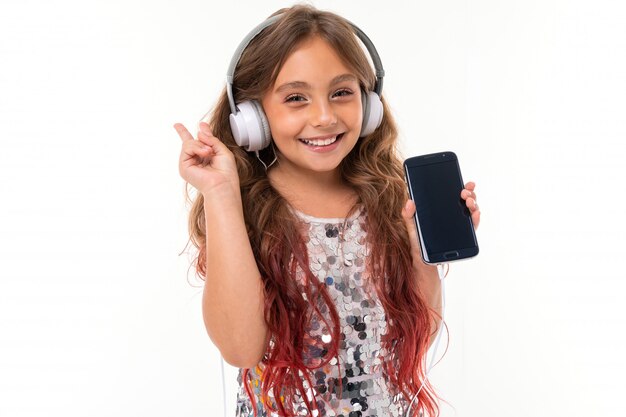 Niña sonriente de pie con el teléfono en sus manos