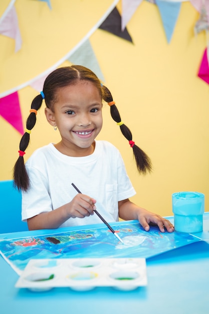 Niña sonriente pintando una imagen