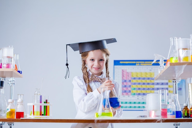 Niña sonriente posando con sombrero de graduado en el laboratorio