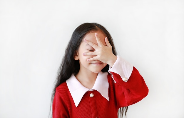 Niña sonriente que cubre los ojos con la mano