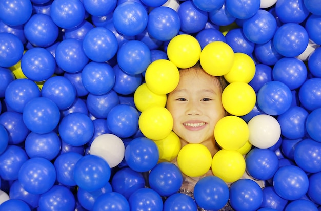 Foto niña sonriente que juega con el patio plástico de las bolas del color.