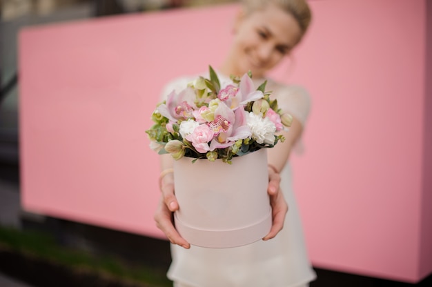 Foto niña sonriente con ramo en caja de sombrero rosa