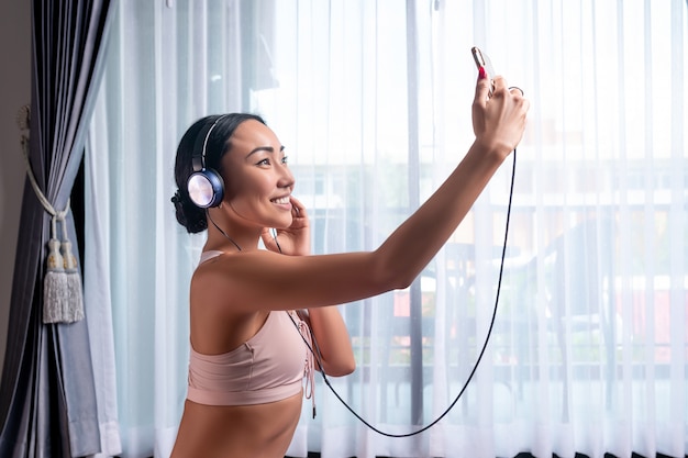 Una niña sonriente de raza mixta, usa auriculares y un teléfono