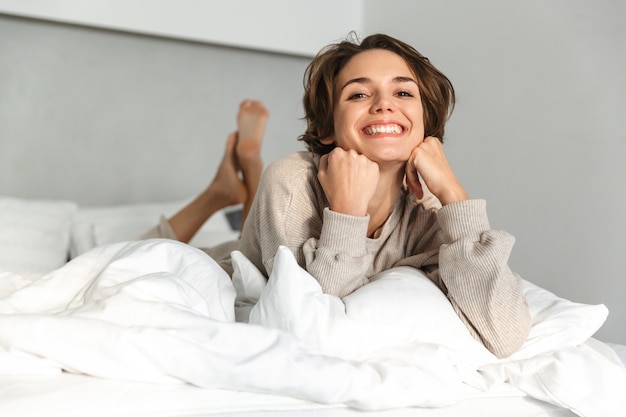 Niña sonriente relajante en la cama por la mañana