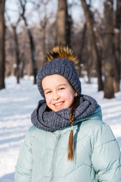 Niña sonriente con ropa abrigada en un parque de invierno en un