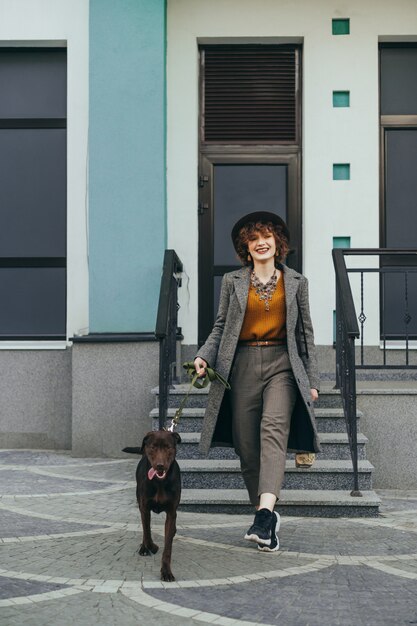 Niña sonriente con ropa elegante y sombrero en un paseo por la calle