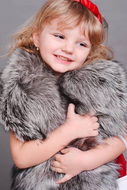 Niña sonriente con ropa de piel sobre gris