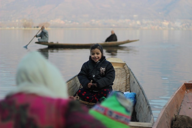 Niña sonriente sentada en un bote en el lago
