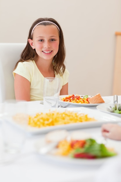 Niña sonriente sentada en la mesa de la cena