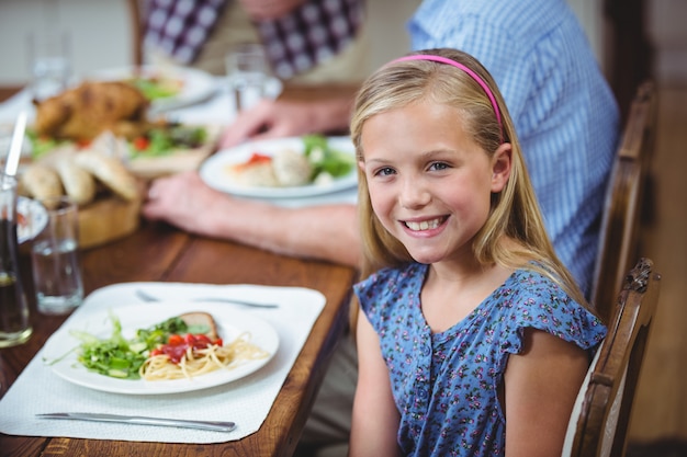 Niña sonriente sentada en la mesa de comedor