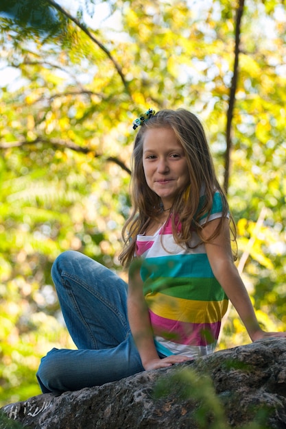 Niña sonriente sentada sobre una piedra en el parque