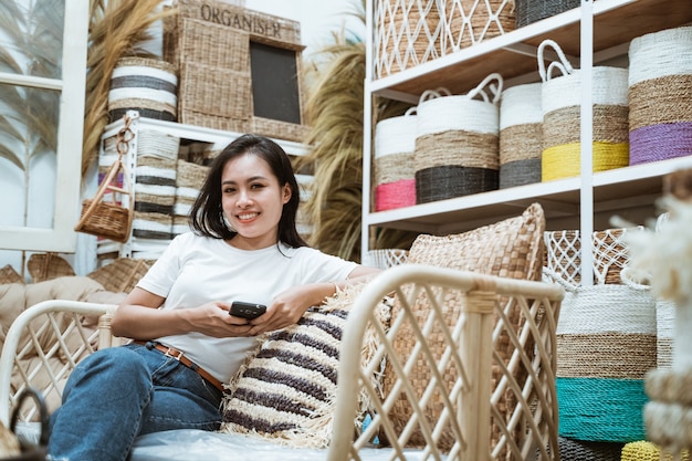 Niña sonriente sentada en el sofá con smartphone en galería de artesanía