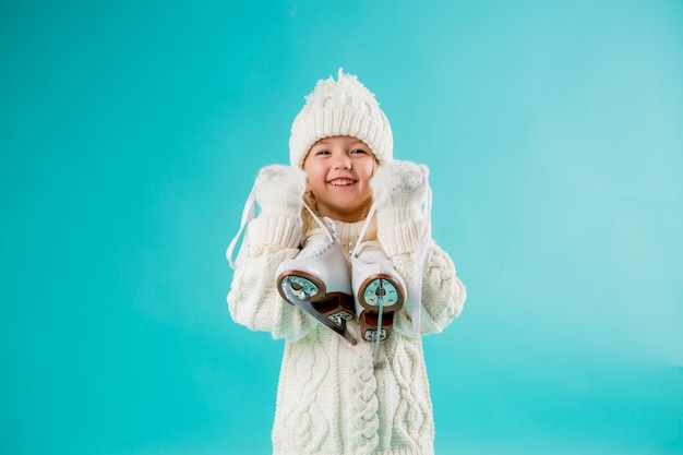 niña sonriente en un sombrero blanco de invierno y suéter
