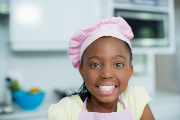 Niña sonriente con sombrero de chef en casa