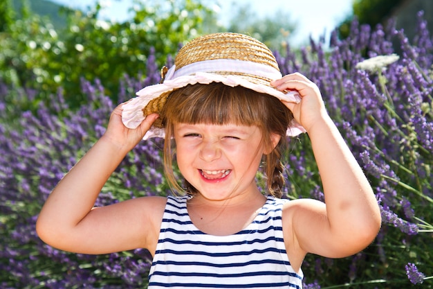 Niña sonriente con sombrero de paja en el campo de lavanda