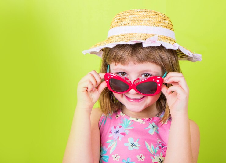 Niña sonriente con sombrero de paja y gafas de sol