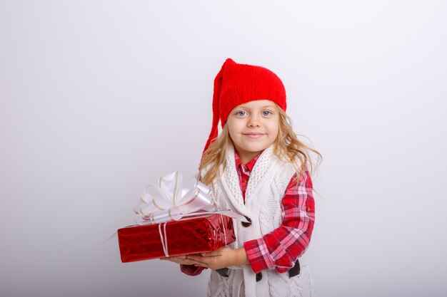 Niña sonriente con sombrero de Santa con caja de regalo aislado sobre fondo blanco.