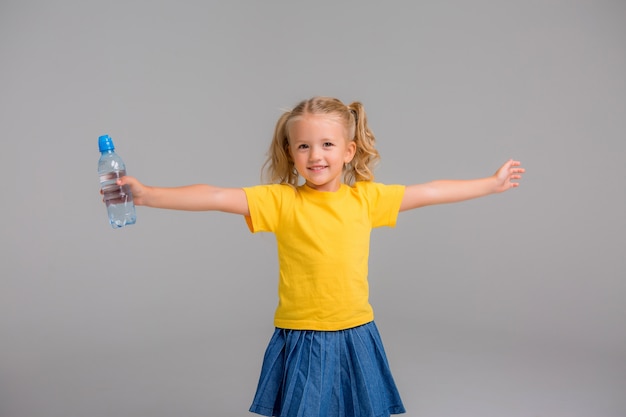 niña sonriente sosteniendo una botella de agua