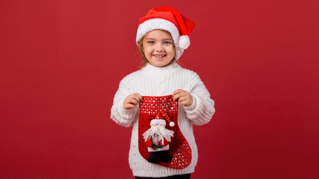 Foto niña sonriente sosteniendo un calcetín de navidad