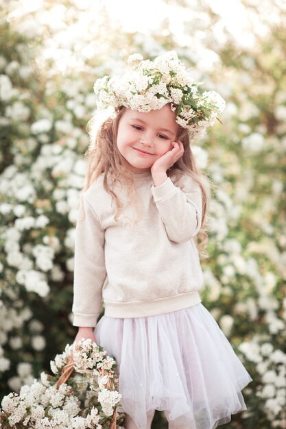 Niña sonriente sosteniendo una canasta con flores al aire libre