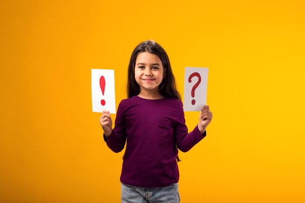 Foto niña sonriente sosteniendo tarjetas con signo de interrogación y punto de exclamación conceptos de idea y conocimiento de los niños