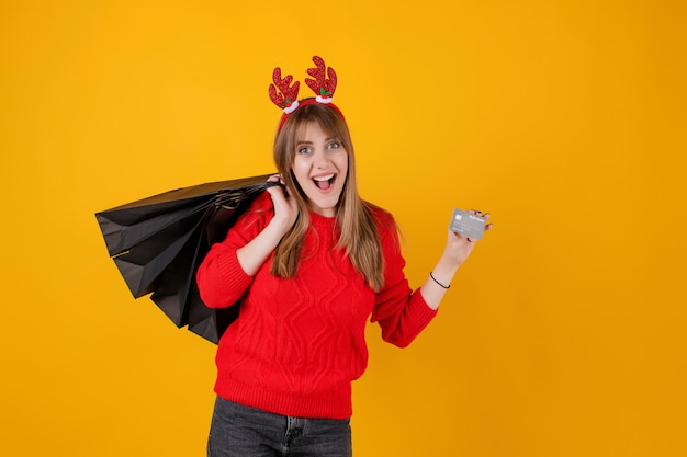 Foto niña sonriente con tarjeta de crédito de plantilla y bolsas de regalo de compras navideñas con aro divertido