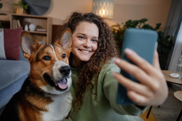 Niña sonriente tomando una foto selfie con un perro feliz en casa