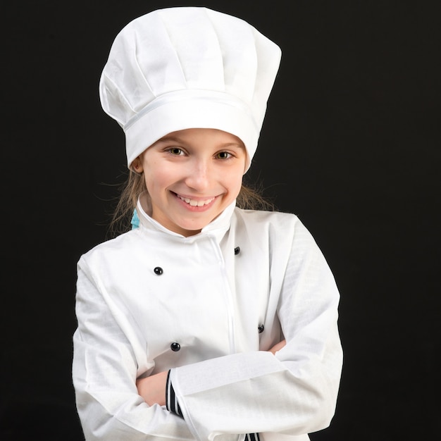 Niña sonriente en traje de chef blanco