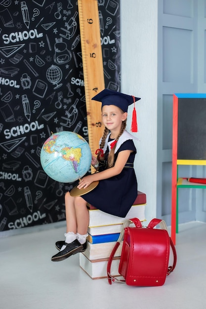 Niña sonriente con uniforme escolar y coletas sosteniendo un globo en el aula.