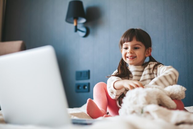 Niña sonriente viendo un video en una laptop