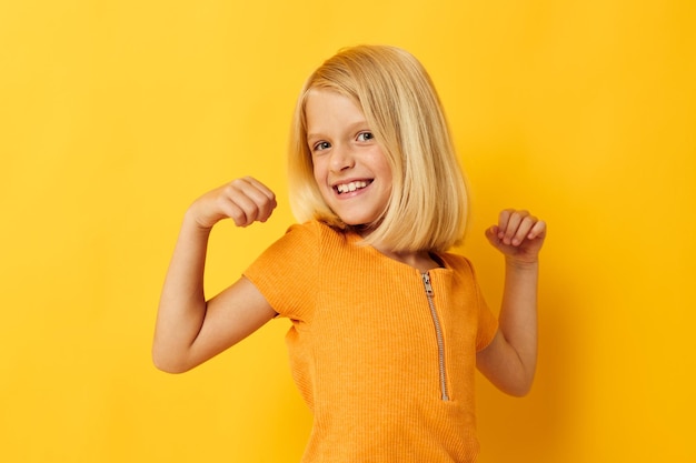 Niña con una sonrisa de camiseta amarilla posando en el estudio estilo de vida infantil inalterado