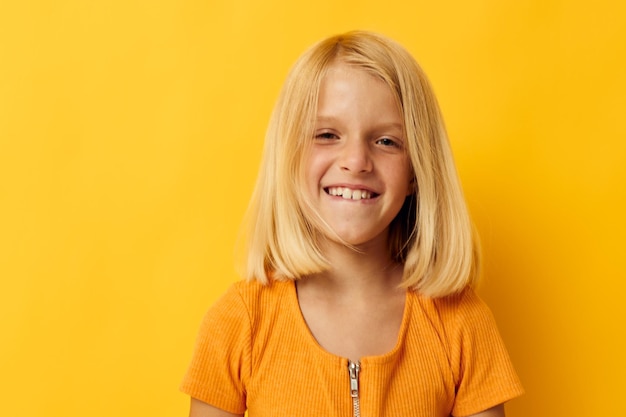 Niña con una sonrisa de camiseta amarilla posando en el estudio estilo de vida infantil inalterado