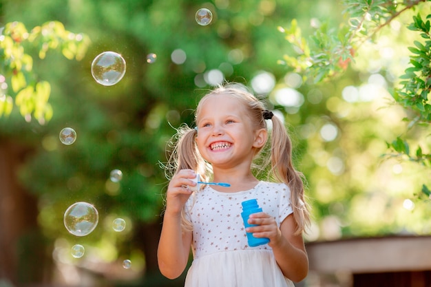 Una niña sopla pompas de jabón en el parque.