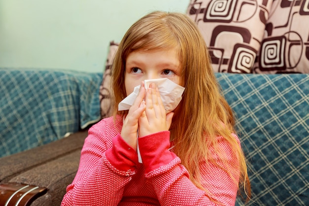 Niña sopla su nariz en un pañuelo de papel