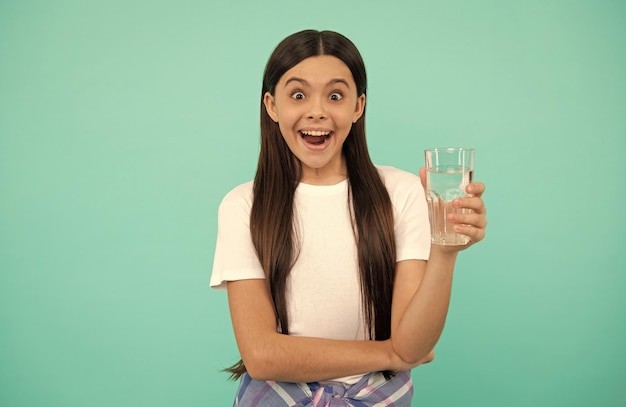 Niña sorprendida bebe un vaso de agua para mantenerse hidratada y mantener el equilibrio diario del agua beber agua