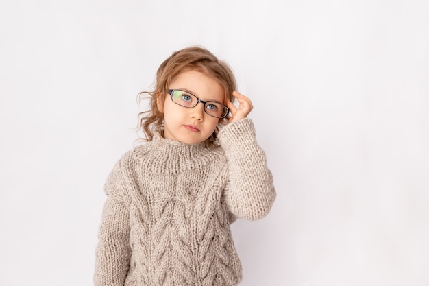 Niña sorprendida con gafas sobre fondo blanco, espacio para texto