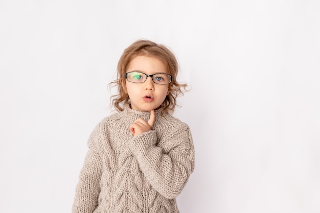 Niña sorprendida con gafas sobre fondo blanco.