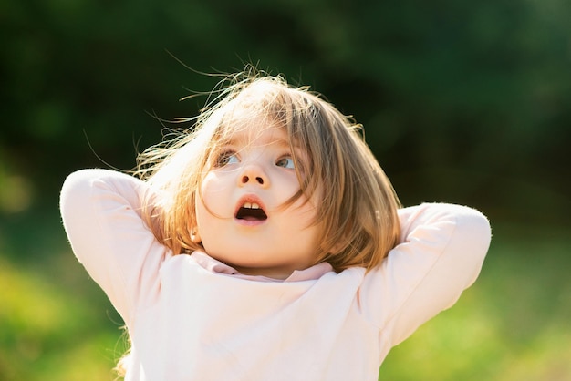 Niña sorprendida en hierba verde en el césped de primavera niños pequeños caminando en el parque bebé emocional fa