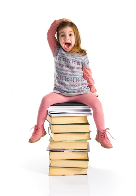 Niña sorprendida sentada en libros. De vuelta a la escuela