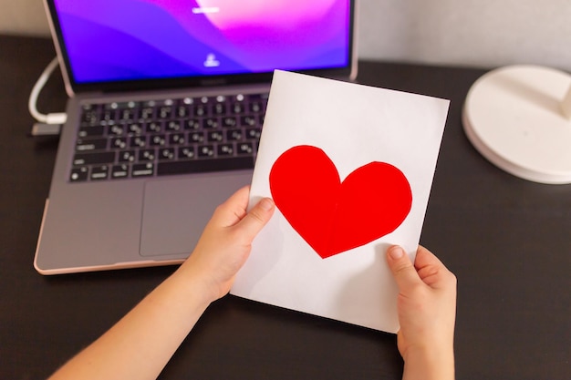 Niña sostenga una postal hecha a mano con un corazón rojo 8 de marzo Cumpleaños del día de San Valentín