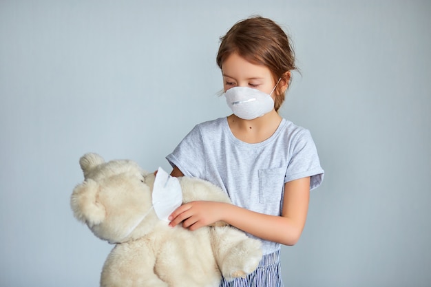 Niña sosteniendo y abrazando a oso de peluche en la máscara.