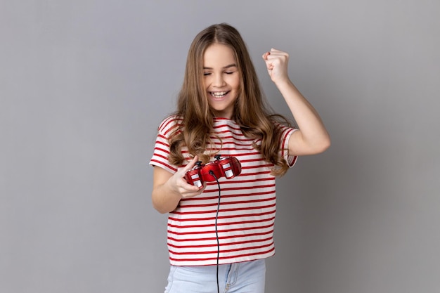 Niña sosteniendo la almohadilla de joystick roja de la mano que muestra un gesto de sí sinceramente regocijándose