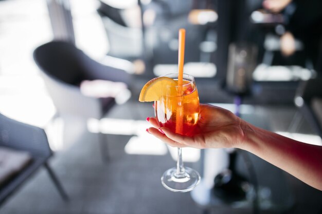 Niña sosteniendo un aperol spritz Cóctel aperol spritz en un vaso Niña en un restaurante con un vaso Aperol spritz en manos de una niña Aperol spritz Cóctel