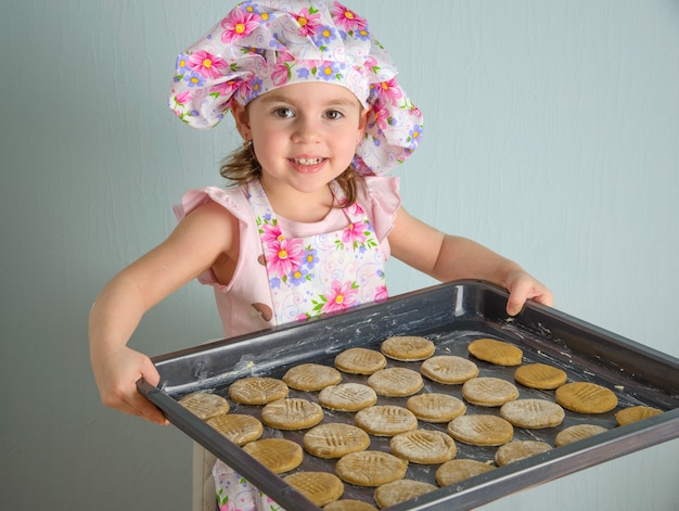 Niña sosteniendo una bandeja de galletas