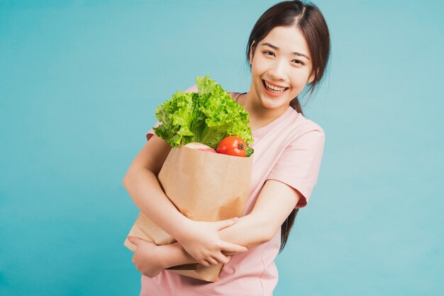 Niña sosteniendo una bolsa de verduras recién compradas en azul