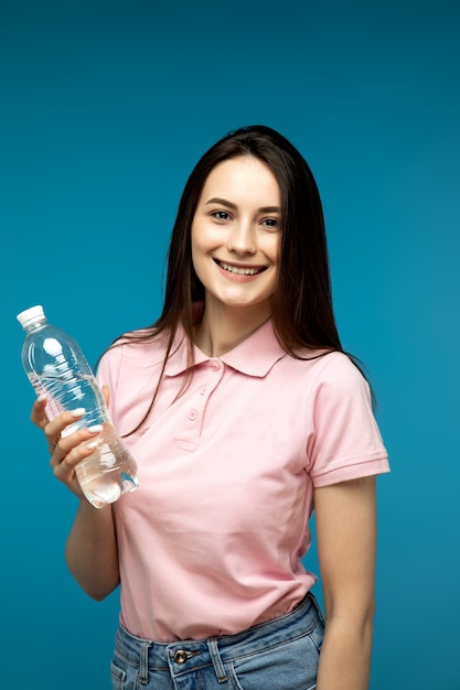 Foto niña sosteniendo una botella de agua sobre fondo azul
