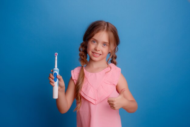 Niña sosteniendo cepillo de dientes eléctrico