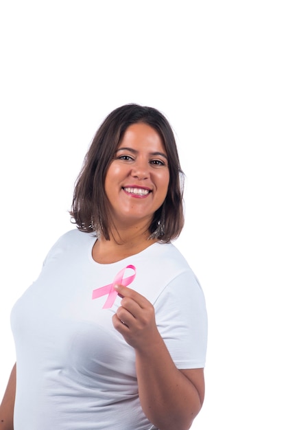 niña sosteniendo la cinta del cáncer de mama sobre un fondo blanco sonriendo.